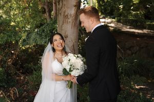 A joyful outdoor wedding scene with natural lighting as a couple stands near a large tree trunk.