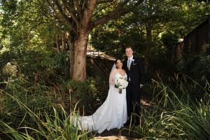 Wedding couple poses together in a serene garden setting surrounded by lush greenery and natural light.