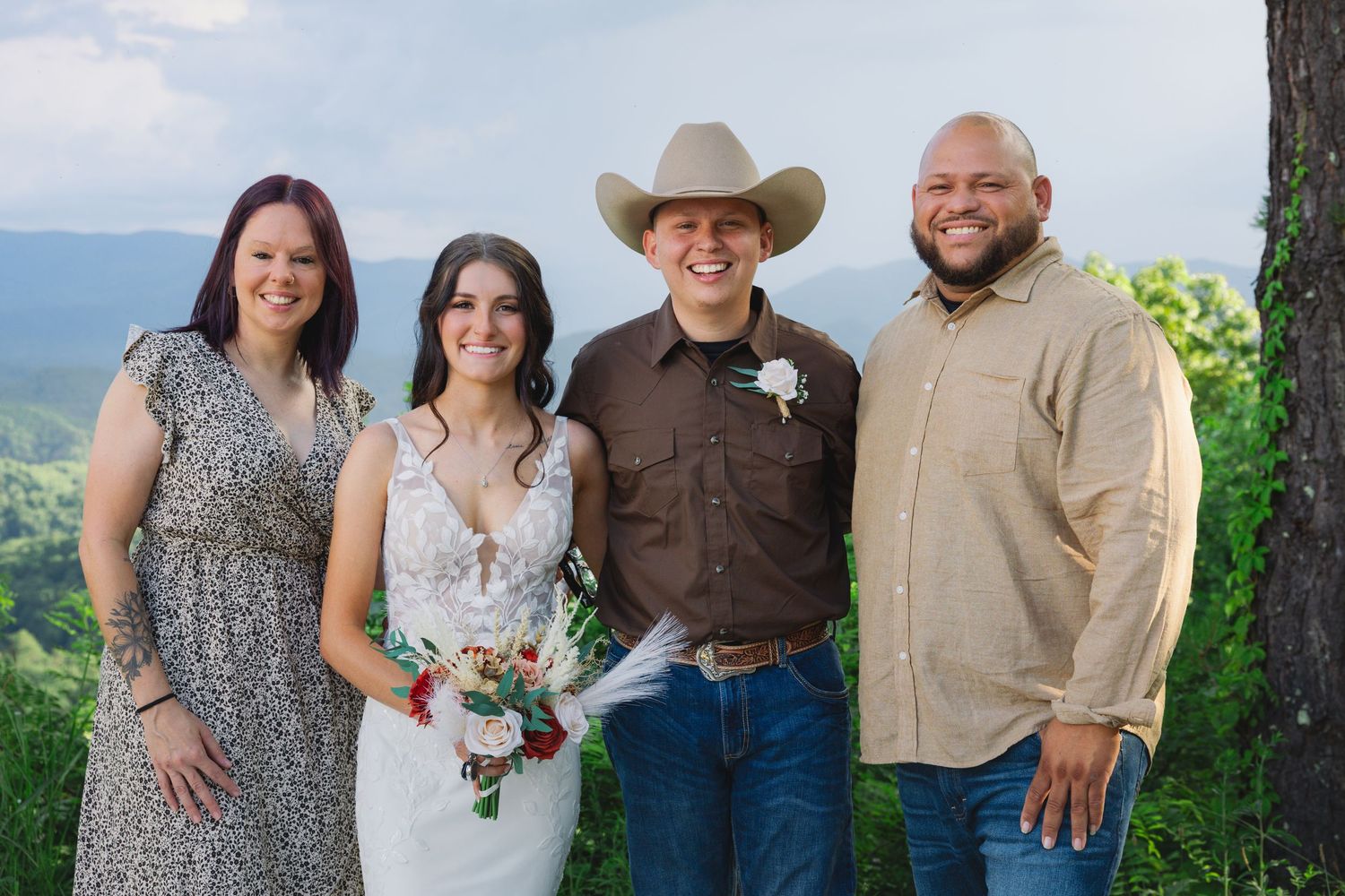 Four people stand together in formal attire against a scenic mountain overlook backdrop.