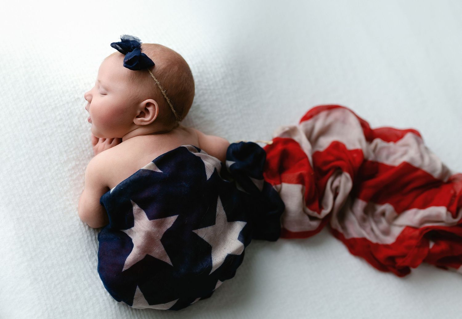 A profile shot of a newborn girl wrapped in an American flag. - Greenville SC newborn photographer - Easley SC newborn photographer