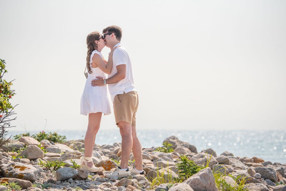 A tender moment between a couple on a scenic rocky beach overlook.