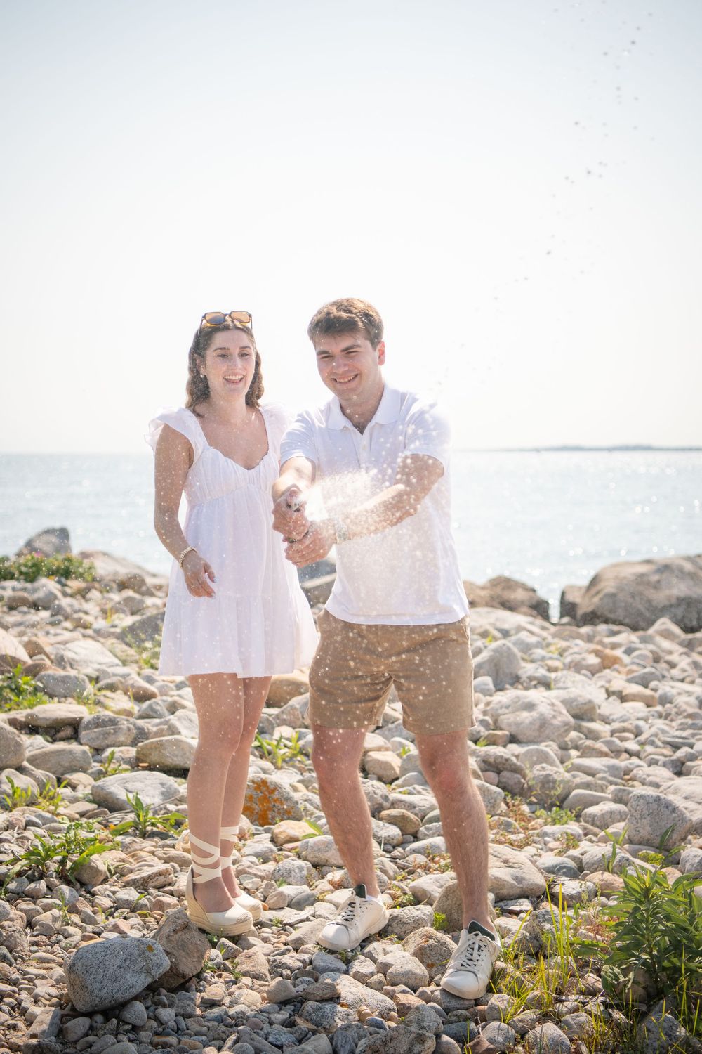 Candid moment of joy captured between two people on a rocky shoreline.