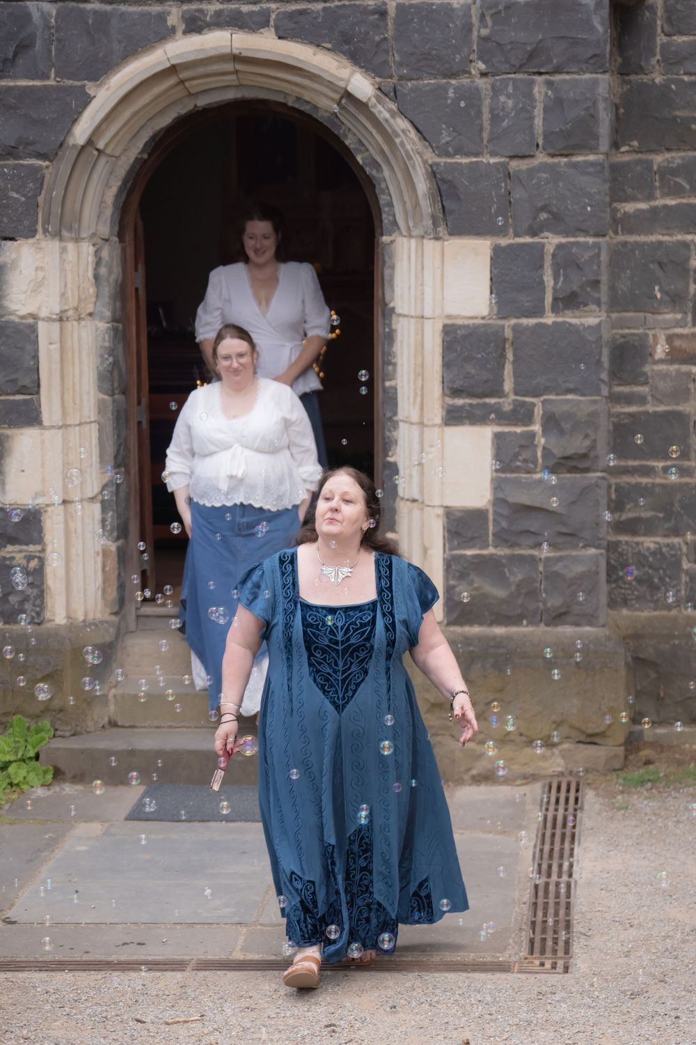 Four sequential photos show a figure in a blue dress dancing and twirling in front of a stone church entrance.