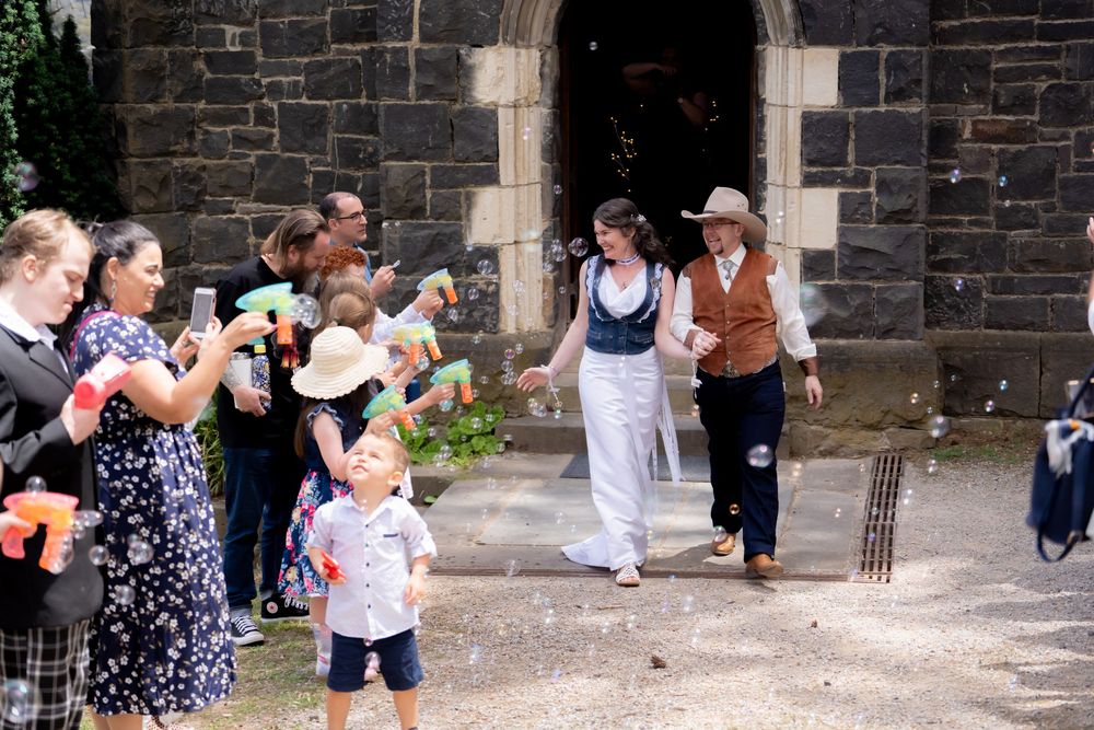 People gather and socialize outside a historic stone church building during what appears to be a summer celebration.