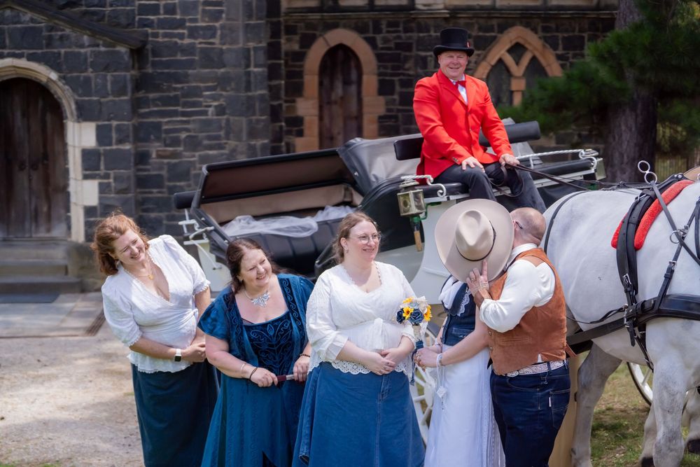 Several couples dance together in front of a brick wall wearing casual formal attire at a social gathering.