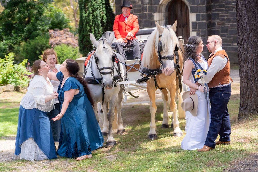 Guests relax on the lawn during an outdoor gathering near stone church walls in summer sunlight.
