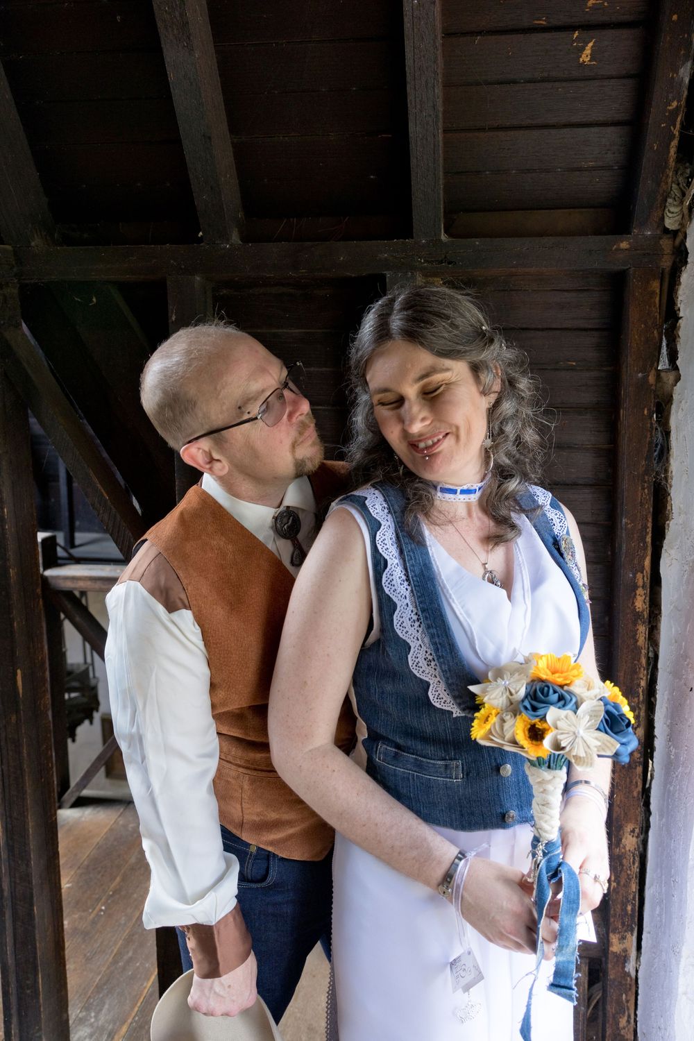Couple sharing an intimate moment on their rustic wedding day, with sunflowers in the bride's bouquet.