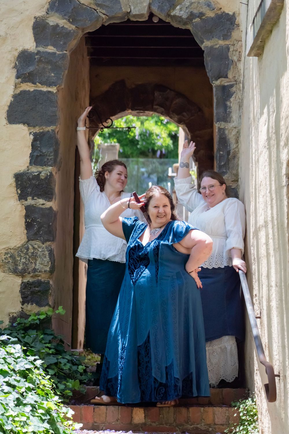 Group standing and waving from stone archways of a historic building.