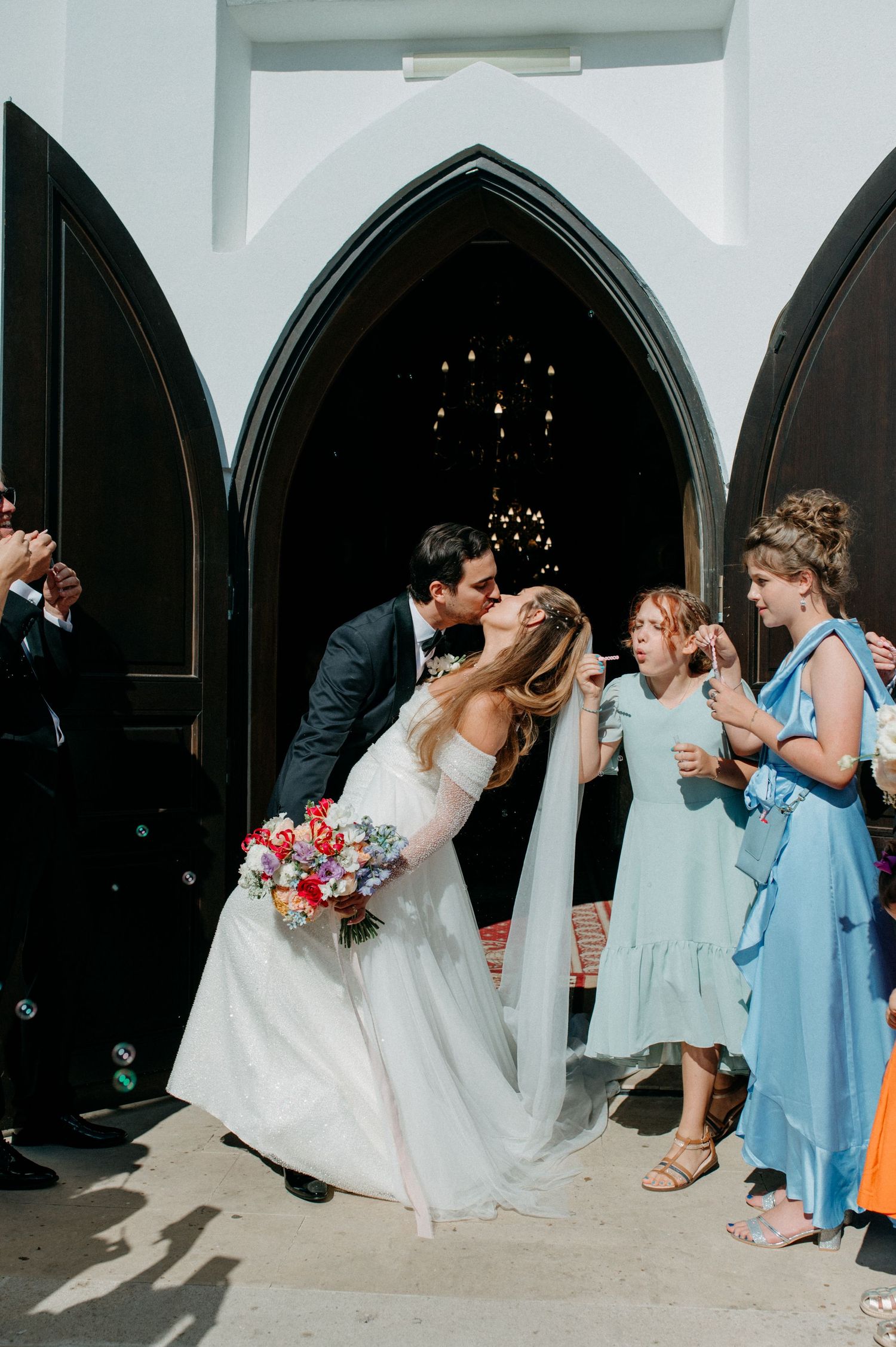 Newly married couple walking out of the church doors, kissing
