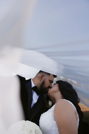 A romantic moment as a couple in wedding attire share a kiss on their special day.