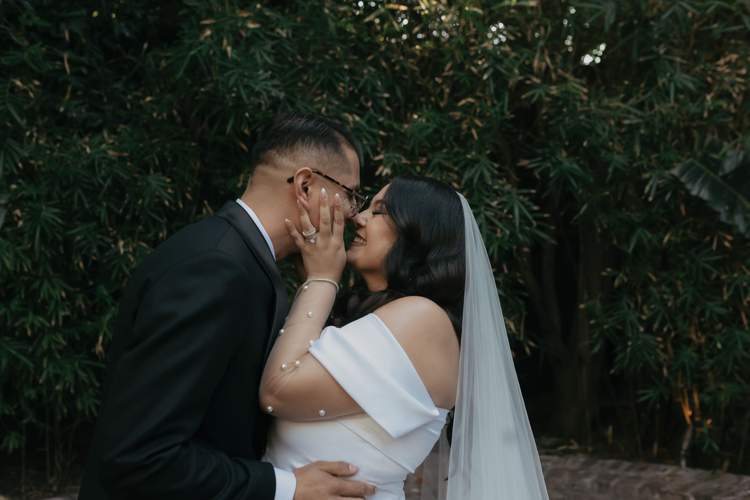 A romantic photoshoot sequence of newlyweds sharing intimate kisses in an outdoor garden setting with lush greenery.
