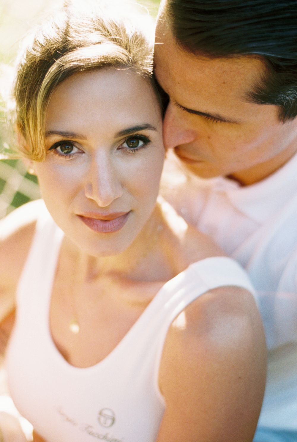 An intimate romantic close-up sequence showing a tender moment between a couple in soft sunlit lighting.