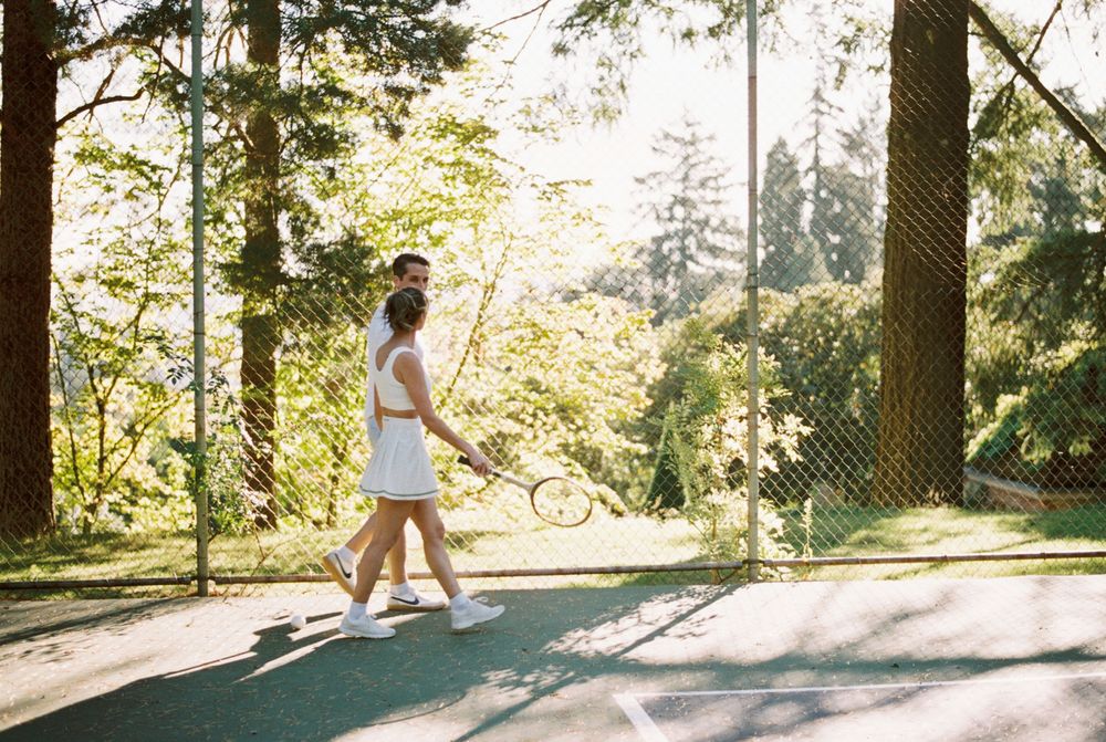 A person wearing white strides through a sunlit forest trail casting long shadows across the dirt path.
