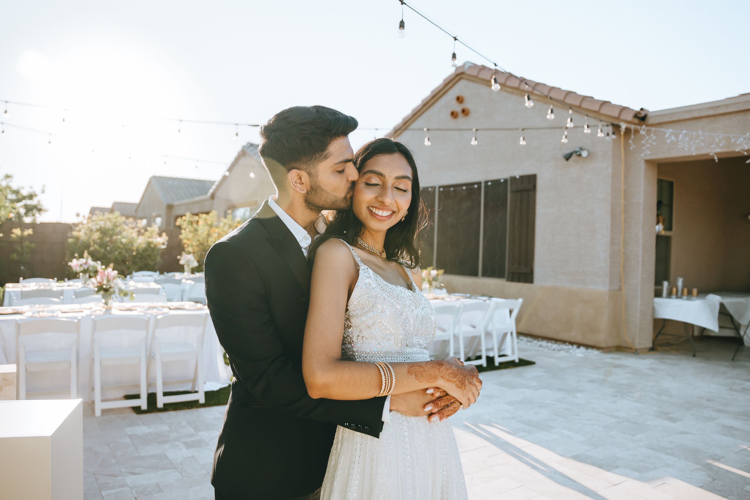 Romantic dance moment captured at outdoor wedding reception with string lights.