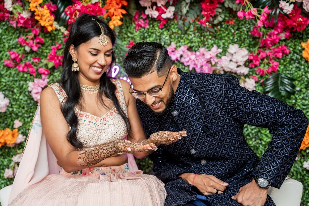A couple shares joyful moments together surrounded by vibrant pink and red flowers in a garden setting.