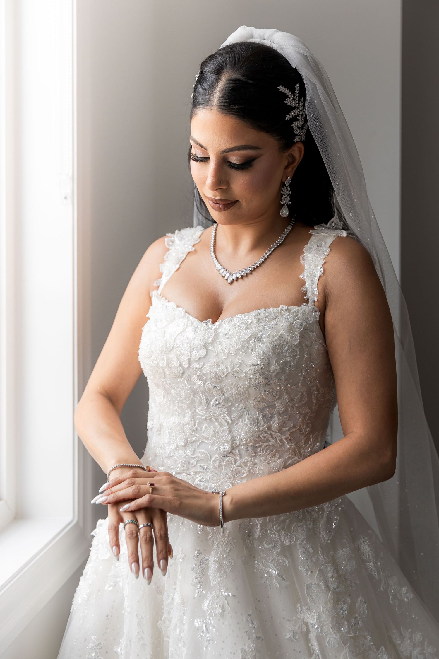 Elegant lace wedding dress details captured in window light.