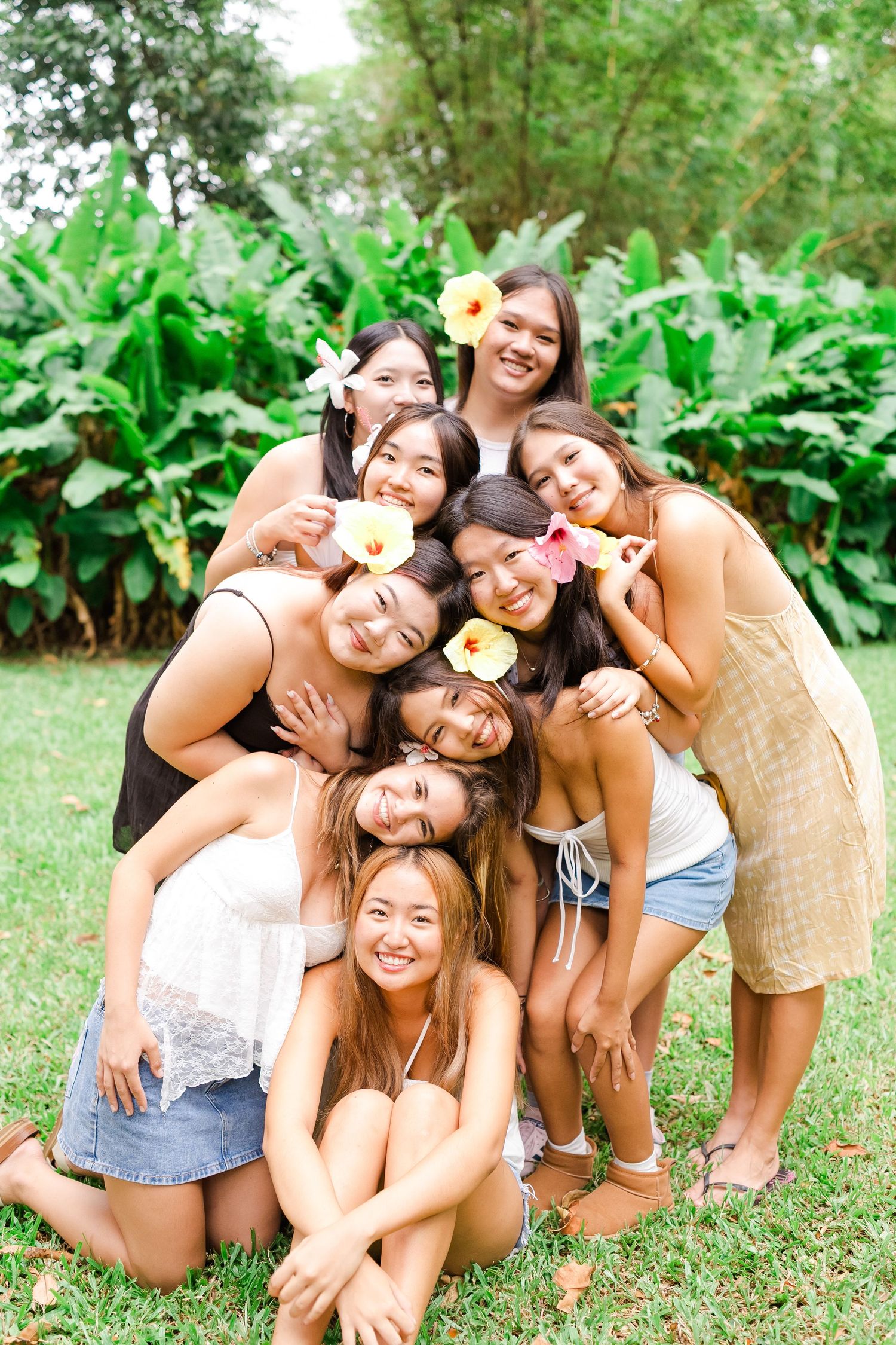 A group of friends pose together outdoors in a lush garden setting with tropical plants in the background.
Oahu family photographer