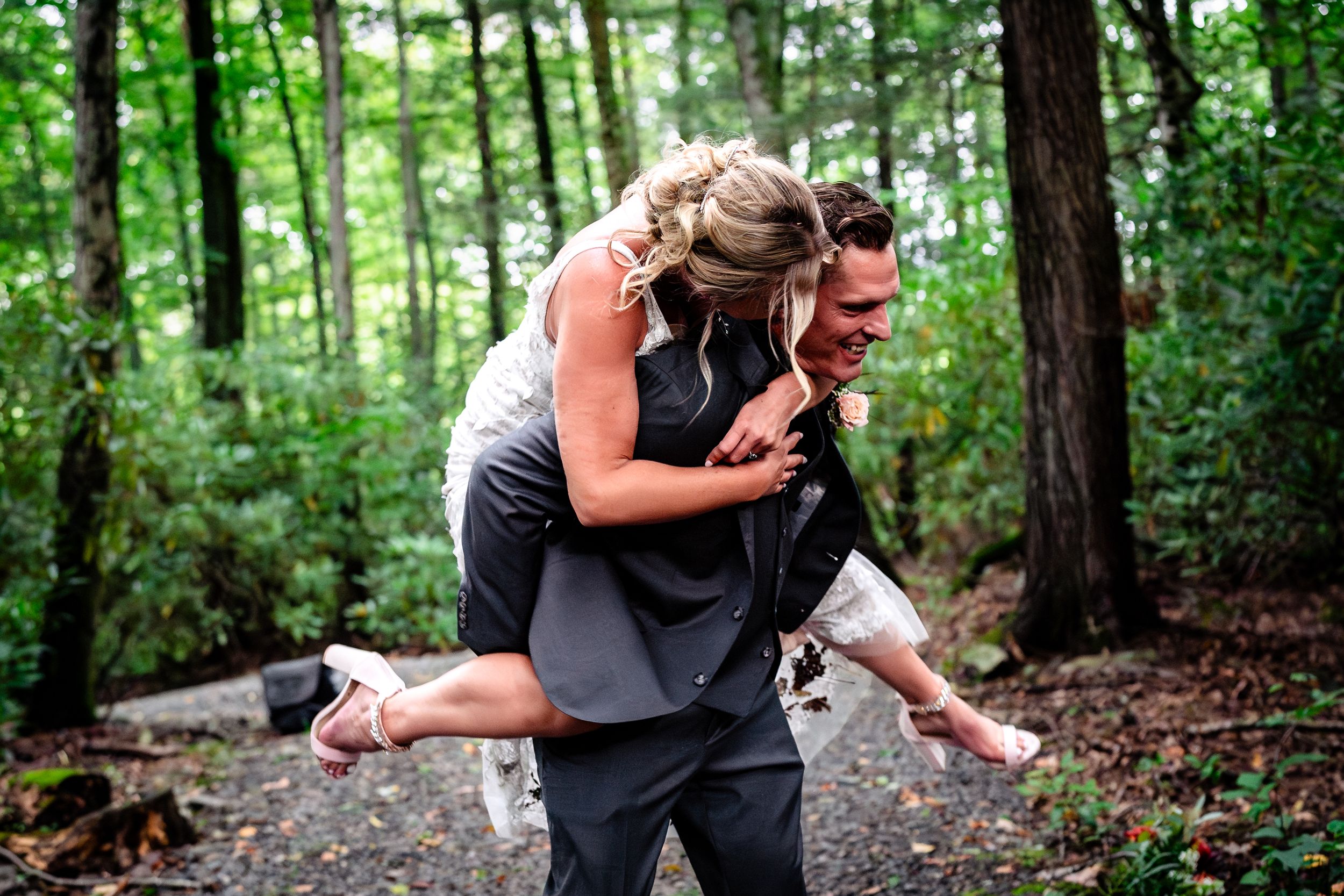 Playful moment captured as couple shares joyful piggyback ride on forest path.