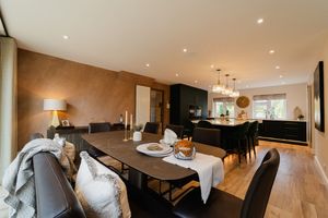 Modern open concept dining and kitchen area with hardwood floors, pendant lights and contemporary dark cabinetry.