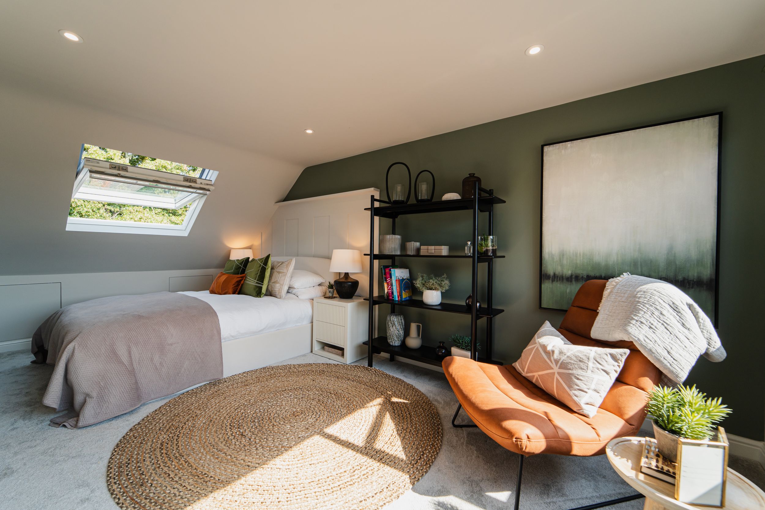 Modern bedroom with gray bedding, rattan rug, orange accent chair, and industrial shelving unit in a cozy attic space.