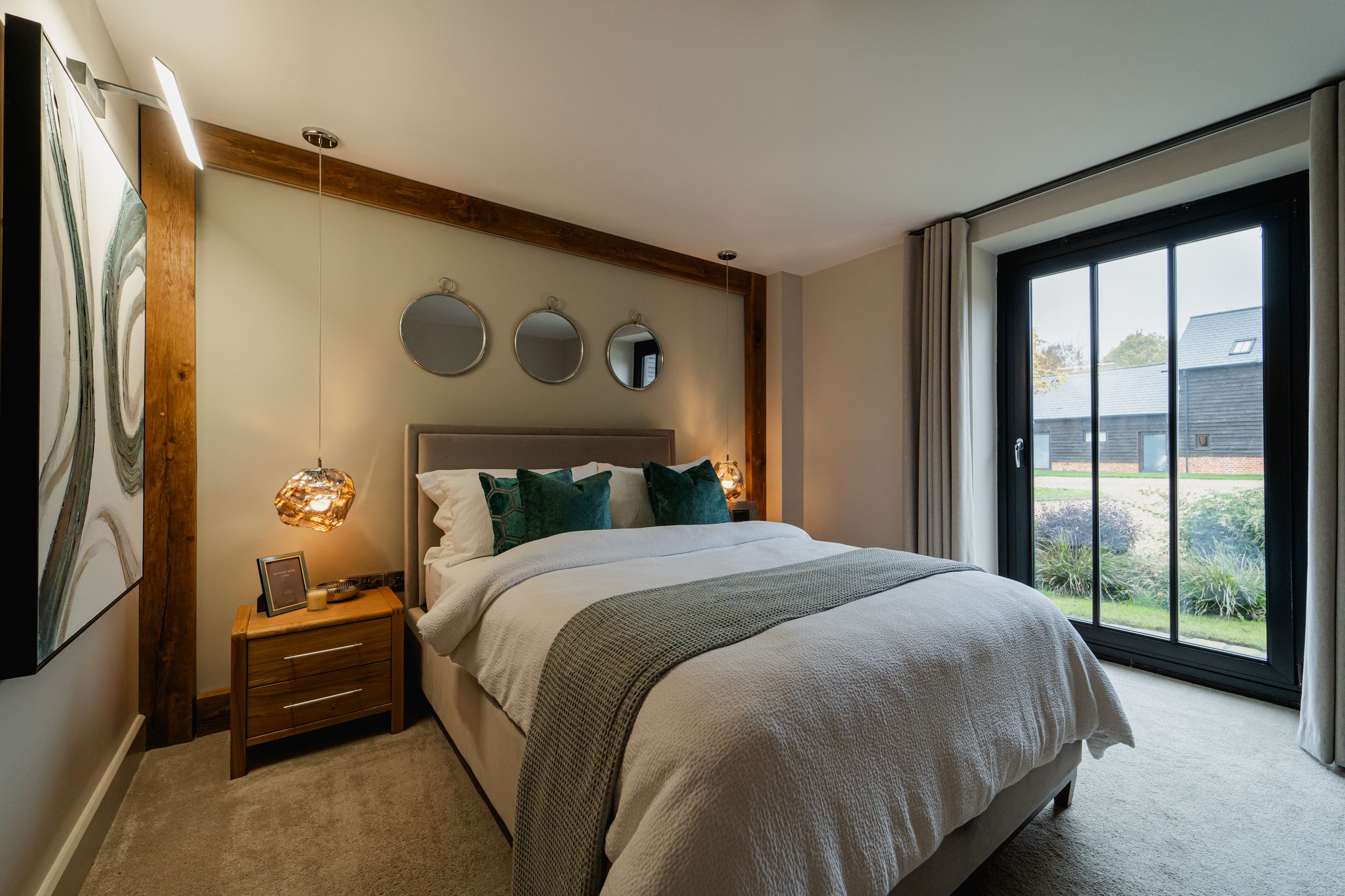 Modern hotel suite features a sleek black glass wall divider and crisp white bedding in a minimalist design.