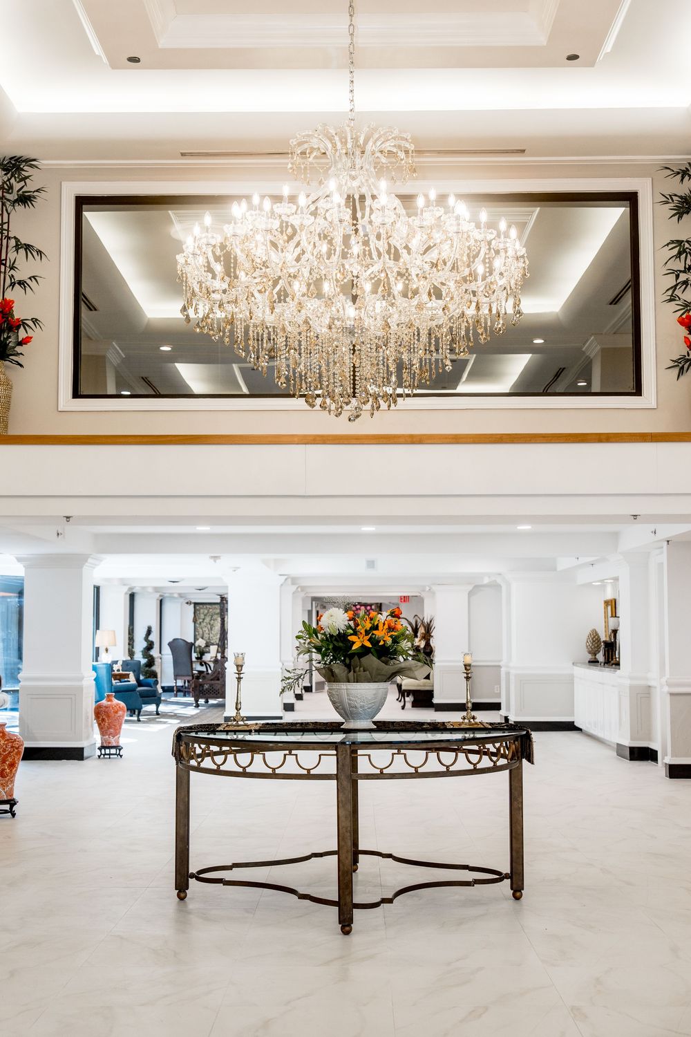 Elegant crystal chandelier illuminates a modern white event space with rustic wooden dividers and polished floors.