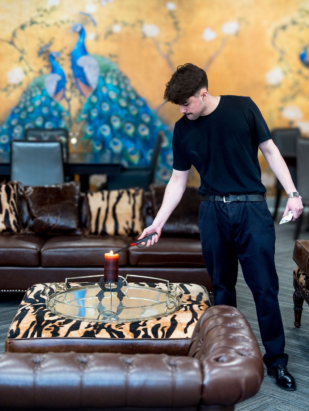 Professional florist carefully arranging flowers and decor on a brown leather sofa during event setup.