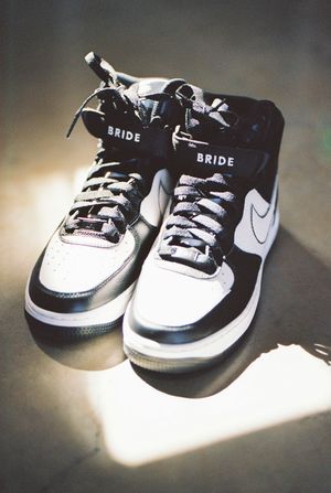 Black and white Nike sneakers with 'BRIDE' branding displayed on a light surface.