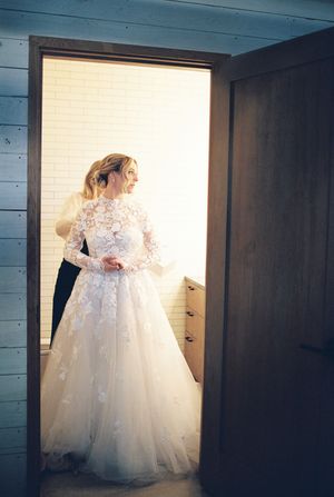 A stunning white lace wedding gown with full tulle skirt photographed in a rustic wooden interior.