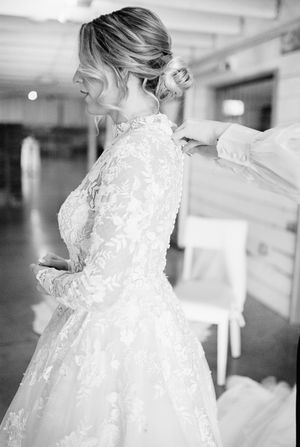 White lace wedding dress with intricate floral details displayed against a light background.