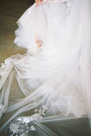 Intricate details of a flowing white wedding dress with delicate lace appliques and tulle layers.