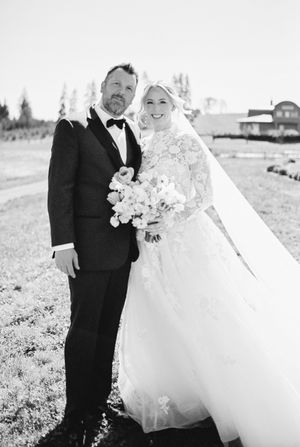 A wedding couple poses outdoors with mountain scenery in a black and white photo.