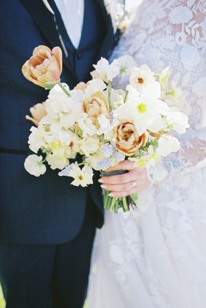 Classic bridal bouquet featuring white and peach blooms with lace dress details.