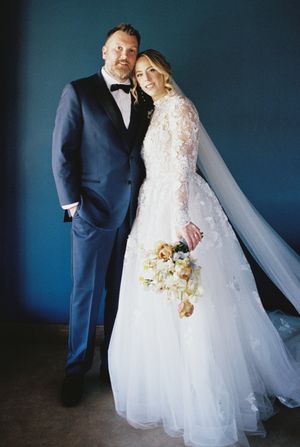 An elegant wedding portrait against a dark blue background.