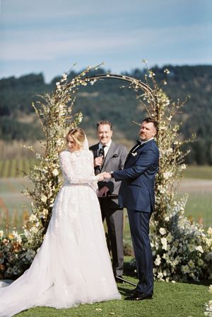 Wedding ceremony under a floral arch with mountains in the background.