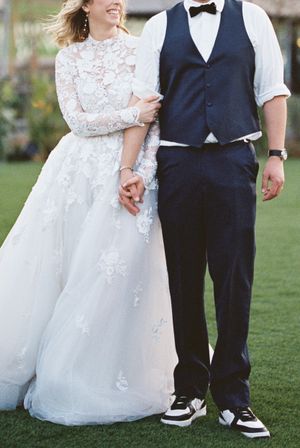 Couple in wedding attire walking outdoors showing contrast of white dress and dark suit.