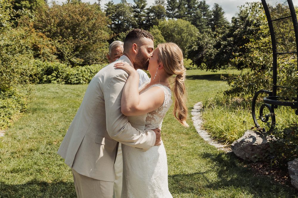 A couple shares romantic wedding moments in a lush garden setting on a bright sunny day.