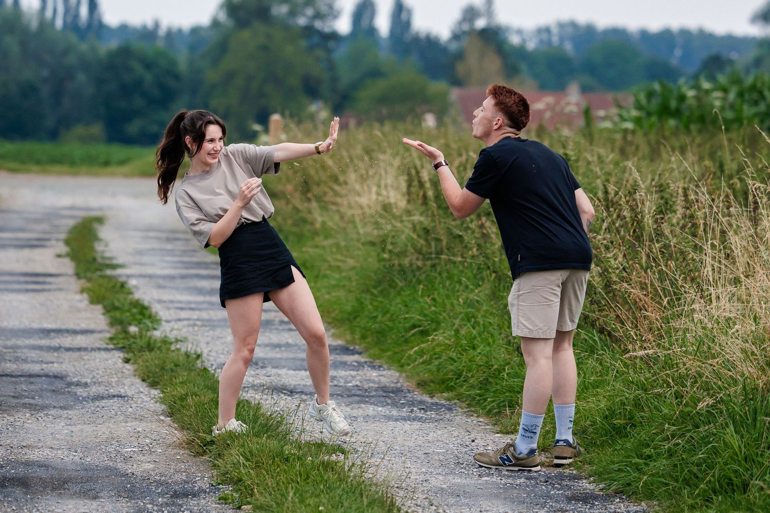 A sequence of people stretching next to gravel path in a grassy field on a sunny day.