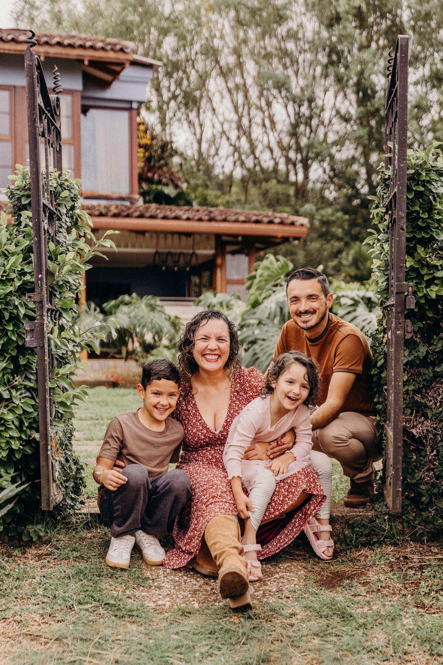 A family poses together in front of a lush garden wall with vibrant greenery.