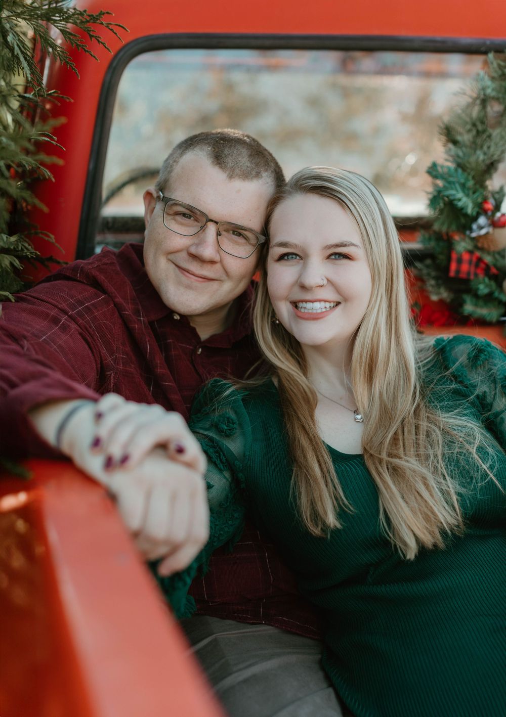 A cozy winter portrait taken through the window of a vintage red truck with holiday decorations.