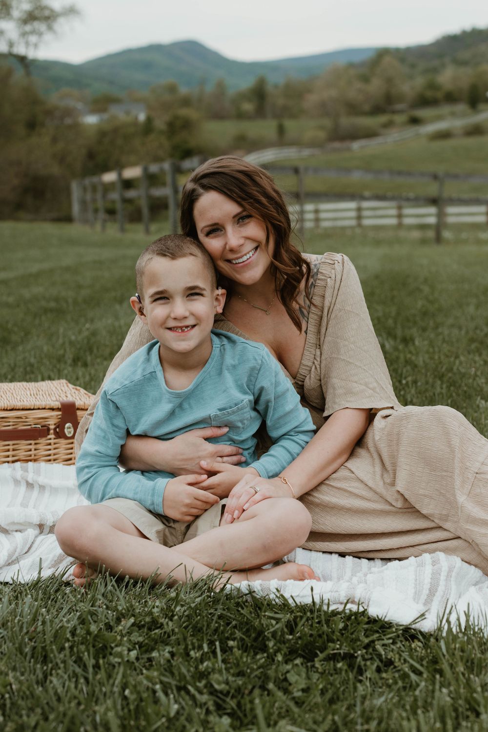 Relaxed outdoor photography session on a white blanket with mountains and fencing in the background.