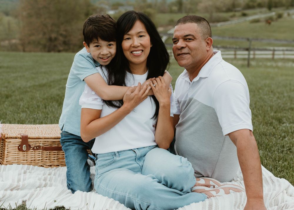 Family enjoying a casual outdoor picnic on a blanket with mountains in the background.