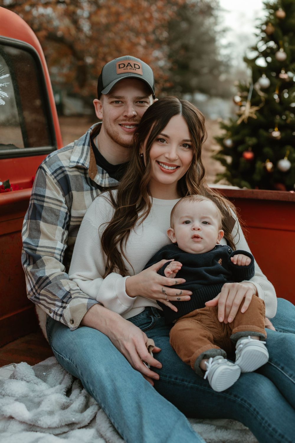 A cozy family photo session in the bed of a vintage red pickup truck during winter.