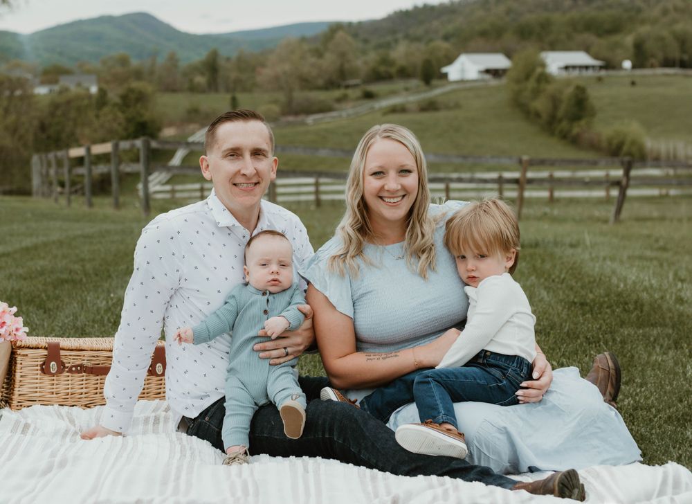 Outdoor family photography session against mountain backdrop with picnic setup.
