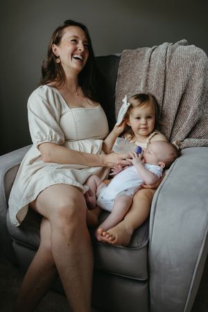 A heartwarming moment on a gray armchair with a baby and toddler.