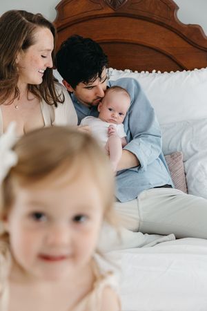 An intimate family moment captured on a wooden headboard bed.