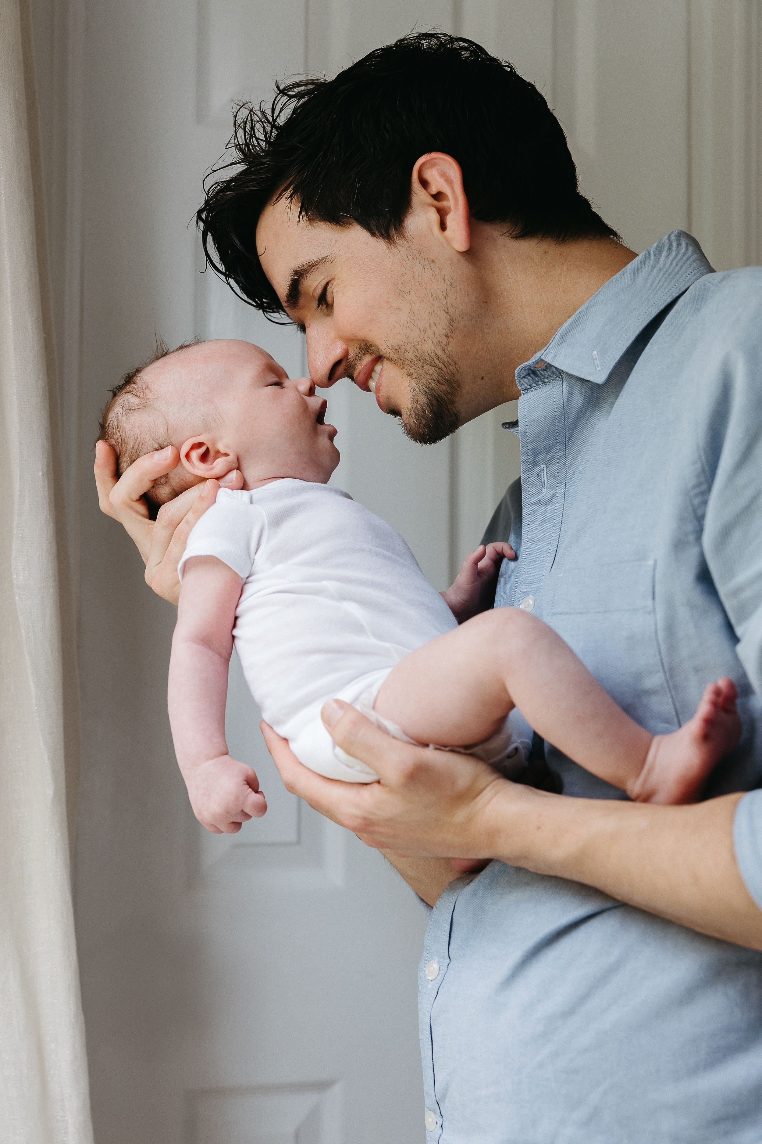 A tender moment between adult and infant as they share a close embrace in soft indoor lighting.