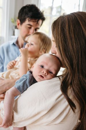 A sweet family scene by a bright window showing tender moments with their children.