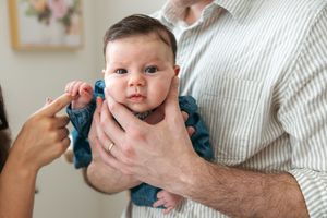 A series of five connected photos showing a baby in teal clothing being held while making different playful expressions.