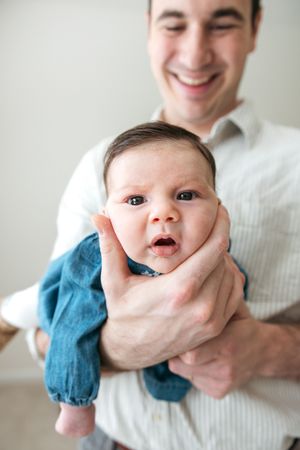 A series of five photos showing a baby in a blue outfit being held and making different playful expressions.